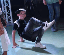 a young boy wearing a hat is doing a handstand on the floor