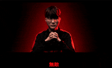 a man with his hands folded in front of a red background with chinese writing on it