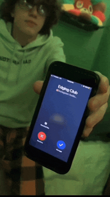 a person holding up a cell phone that says edging club on the screen