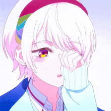 a girl with white hair and a rainbow headband wipes her eyes with her hand