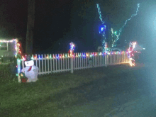 a white fence with christmas lights on it and a snowman