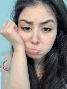 a woman making a sad face with her hand on her face