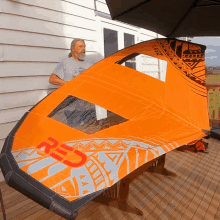 a man is holding an orange kite that says red