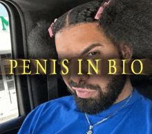 a man with a beard and pigtails is sitting in a car with the words penis in bio behind him .