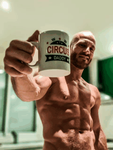 a shirtless man is holding up a coffee mug that says circus daddy