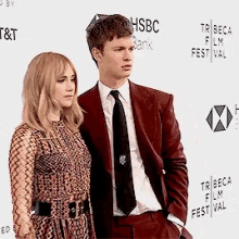 a man and a woman are standing next to each other on a red carpet at a film festival .