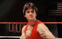 a man in a red tank top stands in a boxing ring with the word u.s. on the wall behind him