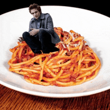 a man sits on a plate of spaghetti with sauce