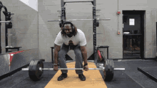 a man wearing headphones is lifting a barbell in a gym with a sign on the wall that says fire alarm