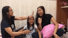 two women and a little girl are playing with pillows in front of a wall that has the word zoro on it