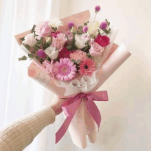 a person is holding a bouquet of pink flowers