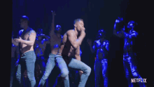 a group of men without shirts are dancing on a stage with a netflix logo in the corner .