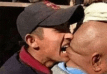 a man in a baseball cap is kissing another man