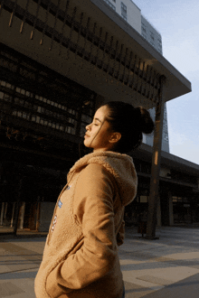 a woman with her eyes closed stands in front of a building that says ' abercrombie & fitch ' on it