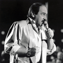 a man with a mustache is singing into a microphone in a black and white photo