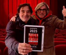 two men holding a book that says agenda 2025 on it