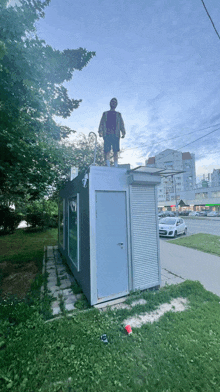 a man is standing on top of a small building with a white car parked in front of it