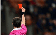 a referee holds up a red card that says genval on the back of his shirt