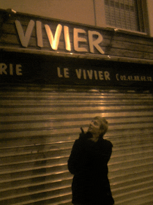 a woman stands in front of a store that says vivier on it