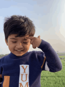 a young boy wearing a sweater that says yum on the front