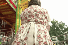 a woman in a floral dress is standing in front of a sign that says ' wurstbrau ' on it