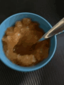 a bowl of food with a spoon in it is on a table .