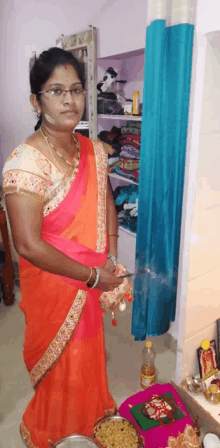 a woman in an orange and pink saree is standing in front of a closet