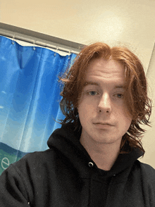 a man with red hair is standing in front of a shower curtain