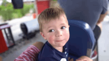 a little boy is sitting in a blue chair looking at the camera