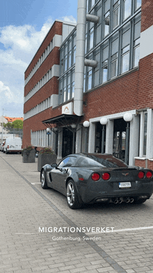 a sports car is parked in front of a building that says migrationsverket on it