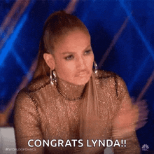 a woman in a gold dress is clapping her hands and saying congrats lynda