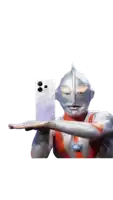 a statue of ultraman is holding a cell phone in his hand