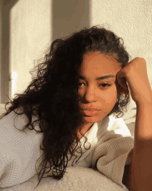 a young woman with curly hair is laying on a bed