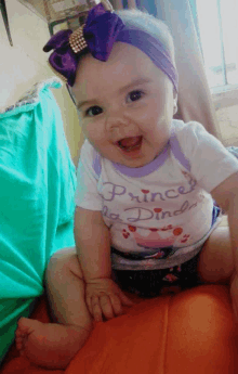 a baby wearing a purple headband and a shirt that says princess on it