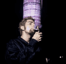 a man smoking a cigarette in front of a sign that says ' amsterdam dance event '