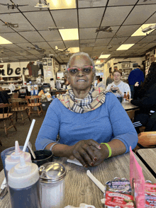 a woman sits at a table in a restaurant with a sign on the wall that says ' amber '