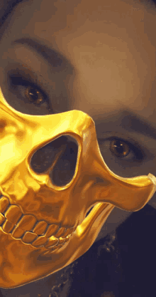 a woman is wearing a gold skull mask