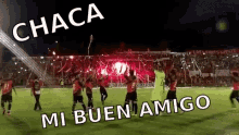 a group of soccer players are dancing on a field with a crowd behind them and the words " chaca mi buen amigo "