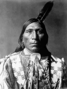 a black and white photo of a man with a feather in his hair