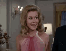 a woman in a pink dress is smiling in a room .