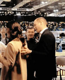 a man in a suit is talking to a woman in a room with a sign on the ceiling that says zanzibar