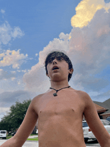 a young boy without a shirt looks up at the sky