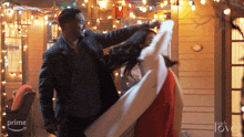 a man and woman are dancing in front of a house with christmas lights and a sign that says " with love "