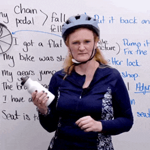 a woman wearing a helmet is holding a water bottle in front of a white board that says " put it back "