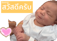 a baby is being held in someone 's arms in front of a sign that says ' สวัสดี ครับ ' on it