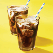 two glasses of iced coffee with blue and white straws on a yellow surface