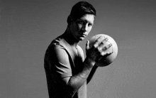 a man in a grey shirt holds a soccer ball in his hands