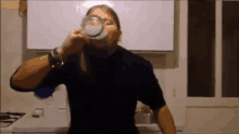 a man drinking from a glass in a kitchen .