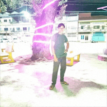 a man stands in front of a tree with a purple light behind him