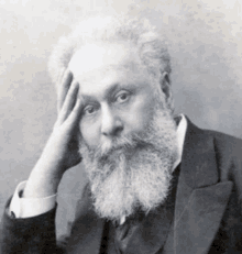 a black and white photo of a man with a beard and mustache in a suit and tie .